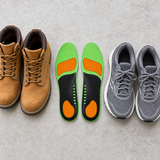 Arch support insoles next to work boots and running shoes